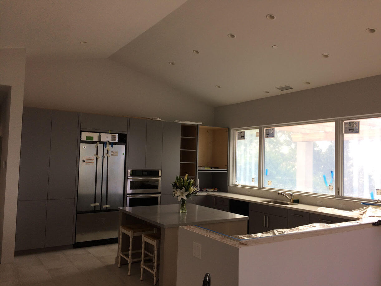 Contemporary kitchen with stainless steel appliances, large windows, and modern cabinets.